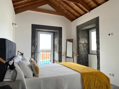 a bedroom with a bed and two windows at Casa do Craveiro in Lajes do Pico