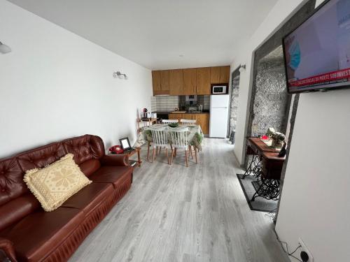 a living room with a brown couch and a table at Casa do Craveiro in Lajes do Pico