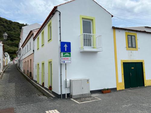 a white building with a green door on a street at Casa do Craveiro in Lajes do Pico
