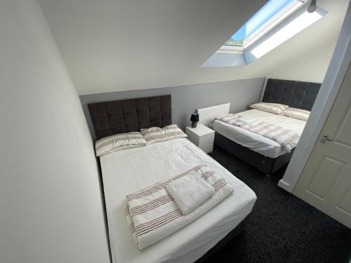 1 dormitorio con 2 camas y ventana en Entire Modern House Halifax en Greetland