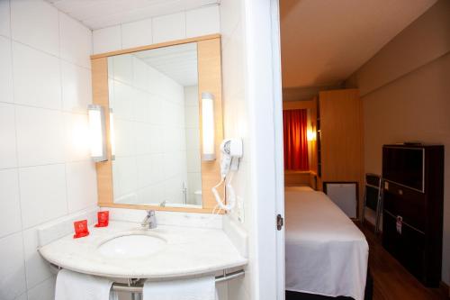 a bathroom with a sink and a mirror and a bed at ibis Recife Boa Viagem in Recife