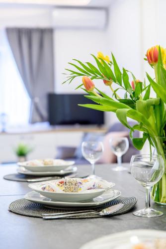 a table with plates and glasses and a vase with flowers at Apartment Solis (****) in Prgomet