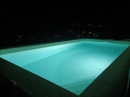 a swimming pool at night with a city in the background at Casa Amarela da Caniçada in Vieira do Minho