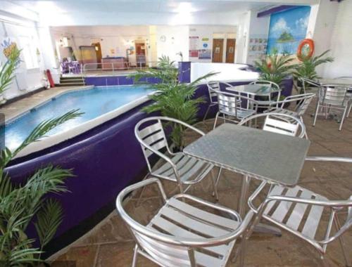 a restaurant with a table and chairs next to a pool at The Long Barn for Families Walker Pets & Workers in Penzance