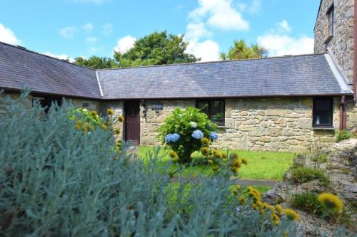 a stone house with a garden in front of it at The Long Barn for Families Walker Pets & Workers in Penzance