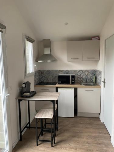 une petite cuisine avec une table et un micro-ondes dans l'établissement joli studio neuf tout equipé, wifi, à Biganos