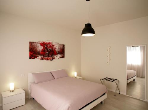 a white bedroom with a bed and a painting on the wall at Melograno Rooms B&B in Brogliano