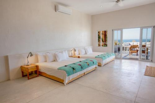 two beds in a bedroom with a view of the ocean at Topia Retreat- Sunset Suite in El Pescadero