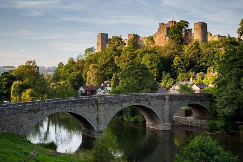 a bridge over a river with a castle in the background at Topsy-Turvy, Gardeners Cottage, Clungunford, Ludlow, Shropshire SY70PN in Broome