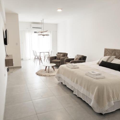 a white bedroom with a bed and a living room at PR Apart - Alquileres Temporarios in San Miguel de Tucumán