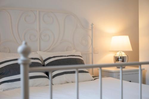 a white bed with a white headboard and a lamp at Luzzu - Family Friendly Maisonette in Xlendi
