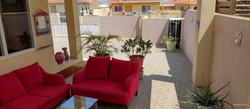 two red chairs sitting on a balcony with plants at Cozy home under the Sun with Swimmingpool in Paradera
