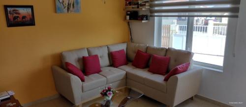 a living room with a white couch with red pillows at Cozy home under the Sun with Swimmingpool in Paradera