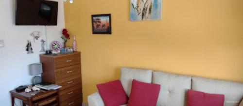 a living room with a white couch and red pillows at Cozy home under the Sun with Swimmingpool in Paradera