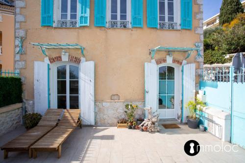 un bâtiment avec des fenêtres bleues et un banc devant lui dans l'établissement Maison climatisée avec vue mer, à Villefranche-sur-Mer
