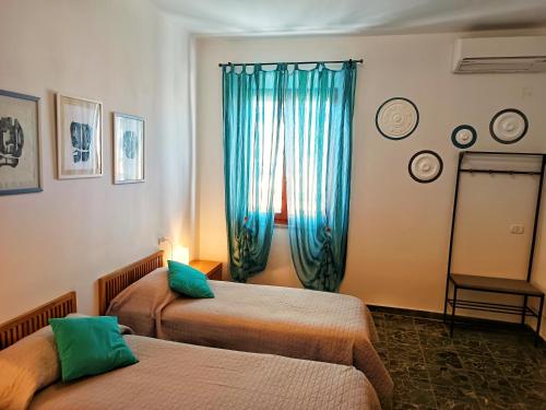 a room with two beds and a window with blue curtains at Lo Zizzolo- Bed&Breakfast in Marina di Campo