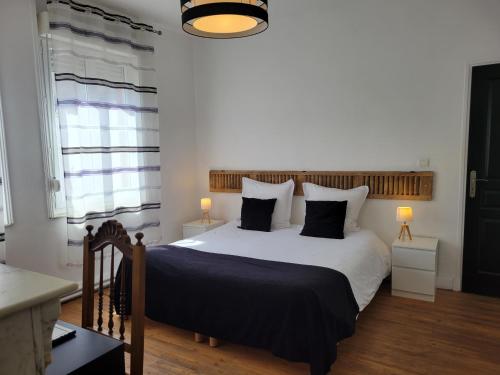 a bedroom with a large bed with black and white pillows at Apt 6 du Temple 2 chambres & Parking in Cambrai