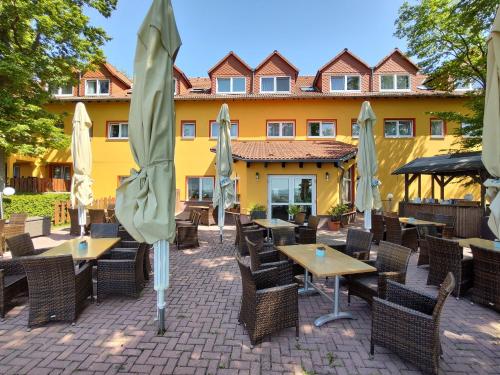 ein Restaurant mit Tischen und Sonnenschirmen vor einem Gebäude in der Unterkunft Hotel-Restaurant Weinberg in Artern