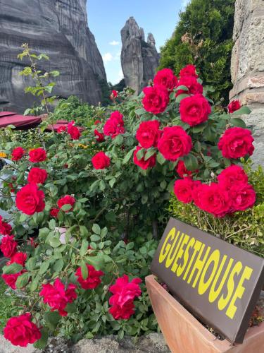 un cartel en un jardín de flores con rosas rojas en Archontiko Mesohori Meteora, en Kalambaka