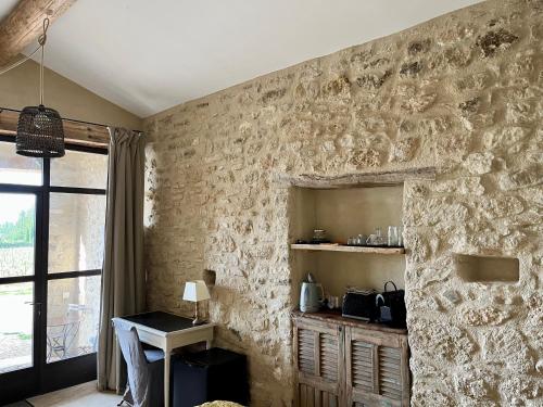 a room with a stone wall with a table and a window at La Verrière à Bonnieux in Bonnieux