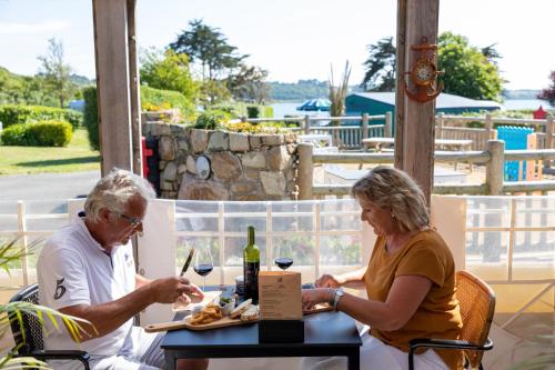 un homme et une femme assis à une table avec du vin dans l'établissement Camping RCN Port l'Epine, à Trélévern