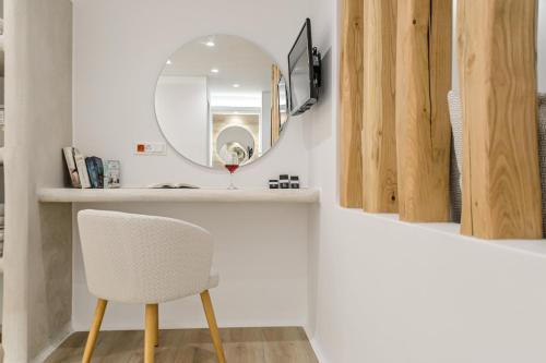 a bathroom with a white chair and a mirror at Villa Adriana Hotel in Agios Prokopios
