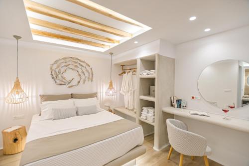 a white bedroom with a bed and a mirror at Villa Adriana Hotel in Agios Prokopios