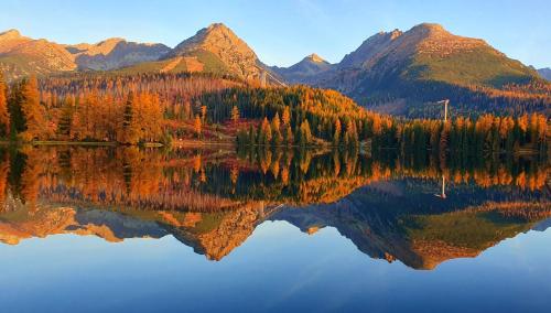 a lake with mountains and a mountain range at Hotel Crocus in Vysoké Tatry