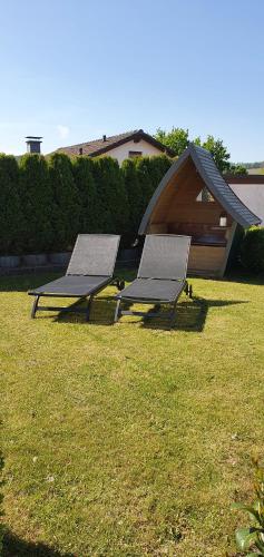 two benches sitting in the grass in a yard at Ferienhaus " Silly " am schönen Listersee in Meinerzhagen