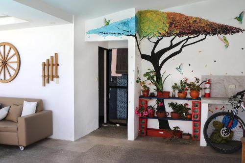a living room with a tree painted on the wall at Hostel las Palmas in Vilcabamba