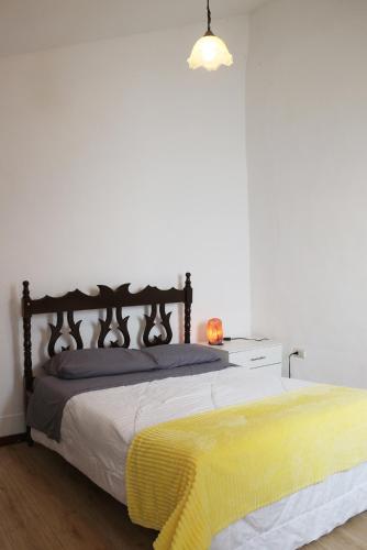 a bedroom with a bed with a yellow blanket on it at Hostel las Palmas in Vilcabamba
