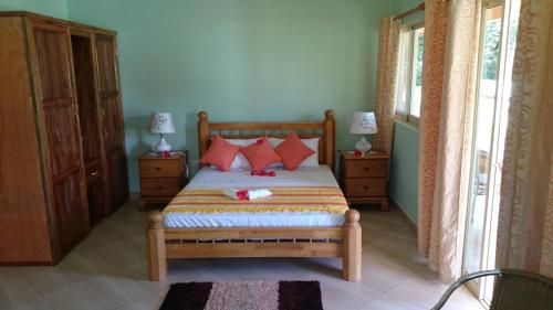 a bedroom with a bed with red pillows at Villa Bedier Self-catering Apartments in Baie Sainte Anne