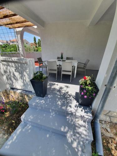 a patio with a table and chairs and flowers at 6 M, 50 m do plaže in Barbat na Rabu