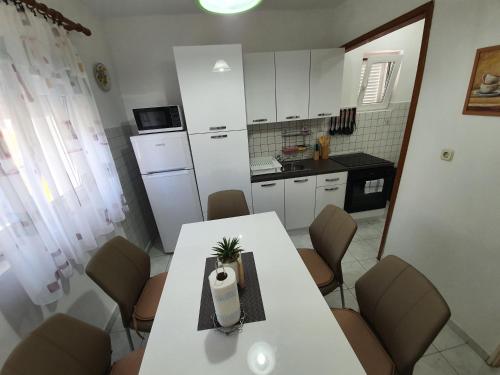 a kitchen with a white table and chairs and a kitchen with a refrigerator at 6 M, 50 m do plaže in Barbat na Rabu
