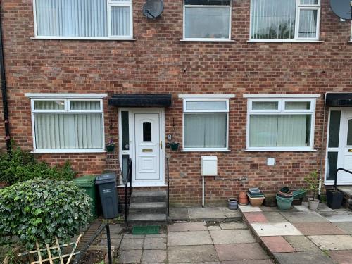 a brick house with a white door and windows at ABIMDOT Exquisite apartments in Manchester