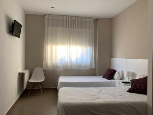Arbeca的住宿－拉普拉克塔旅館，酒店客房设有两张床和窗户。