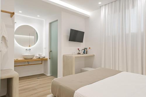 a bedroom with a bed and a sink and a mirror at Villa Adriana Hotel in Agios Prokopios