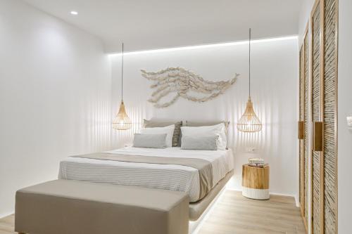a white bedroom with a large bed and two lights at Villa Adriana Hotel in Agios Prokopios