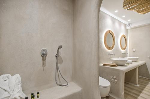 a bathroom with a sink and a toilet and two mirrors at Villa Adriana Hotel in Agios Prokopios