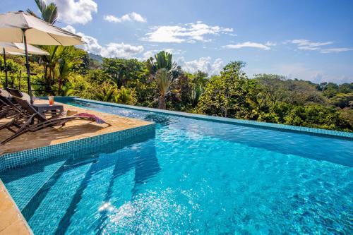 a swimming pool with a chair and an umbrella at Tiki Villas Rainforest Lodge - Adults Only in Uvita