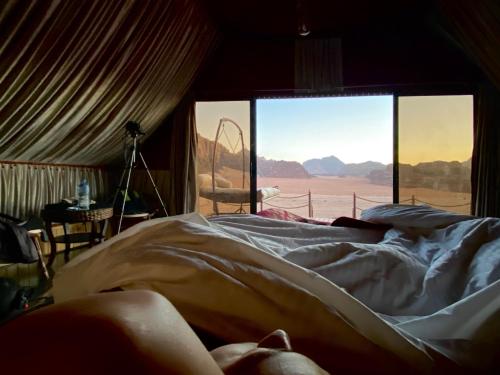 a person laying in a bed in a room with a window at Rum Stars Camp in Wadi Rum