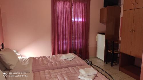 a bedroom with two beds and a red curtain at Porto Sabatiki in Sampatiki