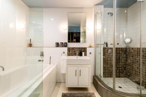 a bathroom with a tub and a sink and a shower at #2004 Cartwright - Glimmer Shimmer in Cape Town