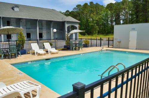 a large swimming pool with chairs and umbrellas at Days Inn by Wyndham Hardeeville Near Hilton Head in Hardeeville
