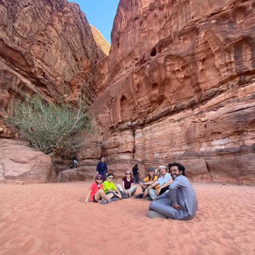 a group of people sitting in the sand near a cliff at Rum Stars Camp in Wadi Rum