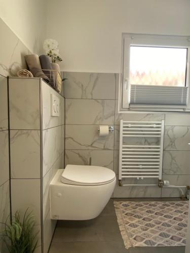 a white bathroom with a toilet and a window at Ferienwohnung Univers 3 in Bad Harzburg