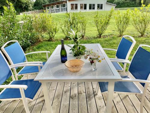 - une table de pique-nique blanche avec une bouteille de vin et des fleurs dans l'établissement Résidence La Ferme de Deauville - Saint Arnoult, à Saint-Arnoult