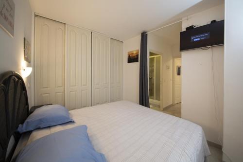 Victoria Appartement في مينتون: غرفة نوم بسرير ابيض مع مخدات زرقاء