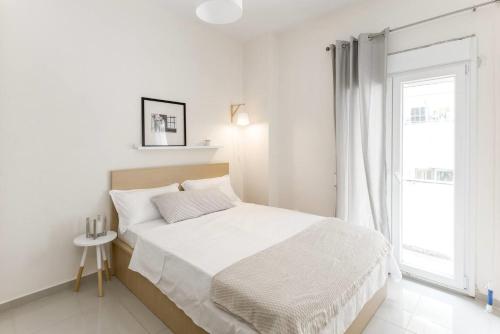 a white bedroom with a bed and a window at HAPPY TRAVELLER - Luxury, Free Parking in Thessaloniki
