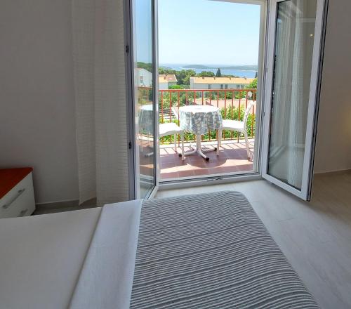 a bedroom with a bed and a balcony with a table at Guest House Mediterranean in Hvar